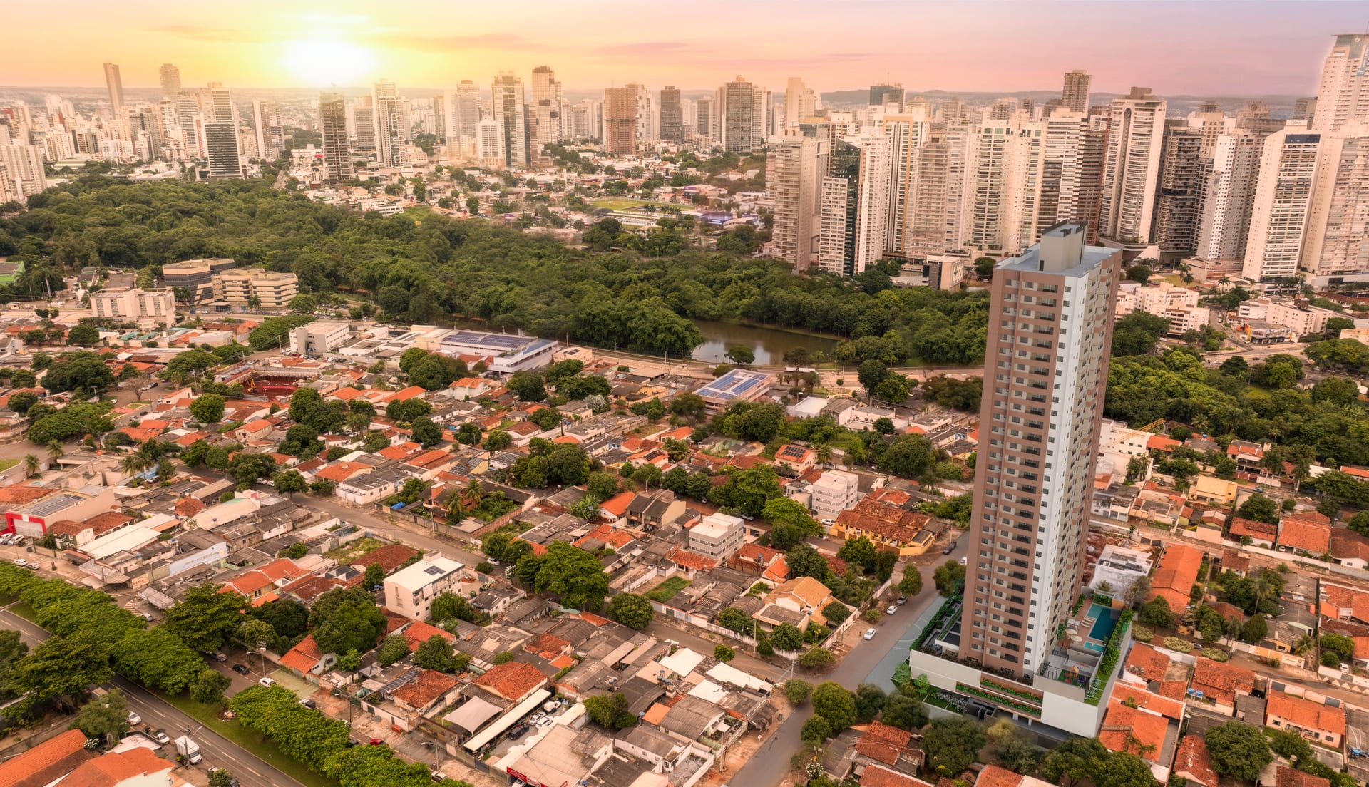 Vista aérea do Una Areião ao entardecer, entre o verde do Parque Areião e o horizonte de Goiânia